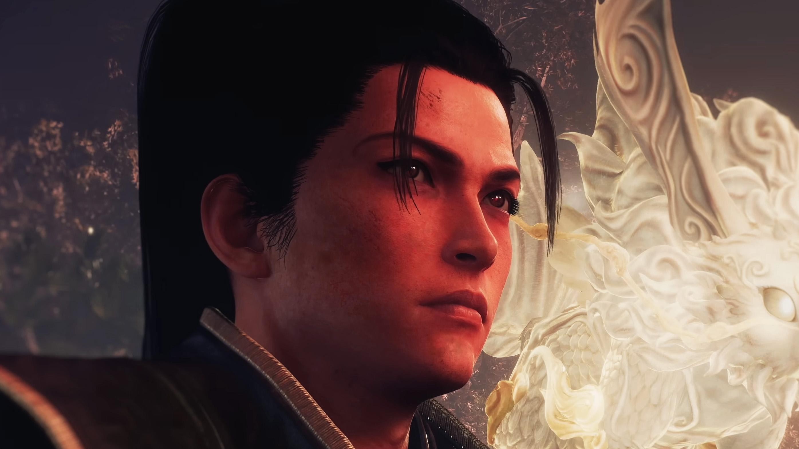 A close-up of the main character of Nioh 3. He has long, black hair put up in a high ponytail and dark brown eyes. He&#039;s looking just off-screen with some sort of spirit creature behind him.