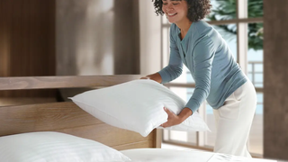 Woman placing Beckham hotel collection pillows on bed