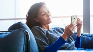 Woman looking at her phone on the sofa, tired