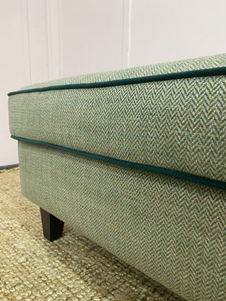 Close up of a green sofa with contrast piping