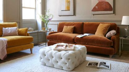 orange sofa in living room with ottoman and panelled walls