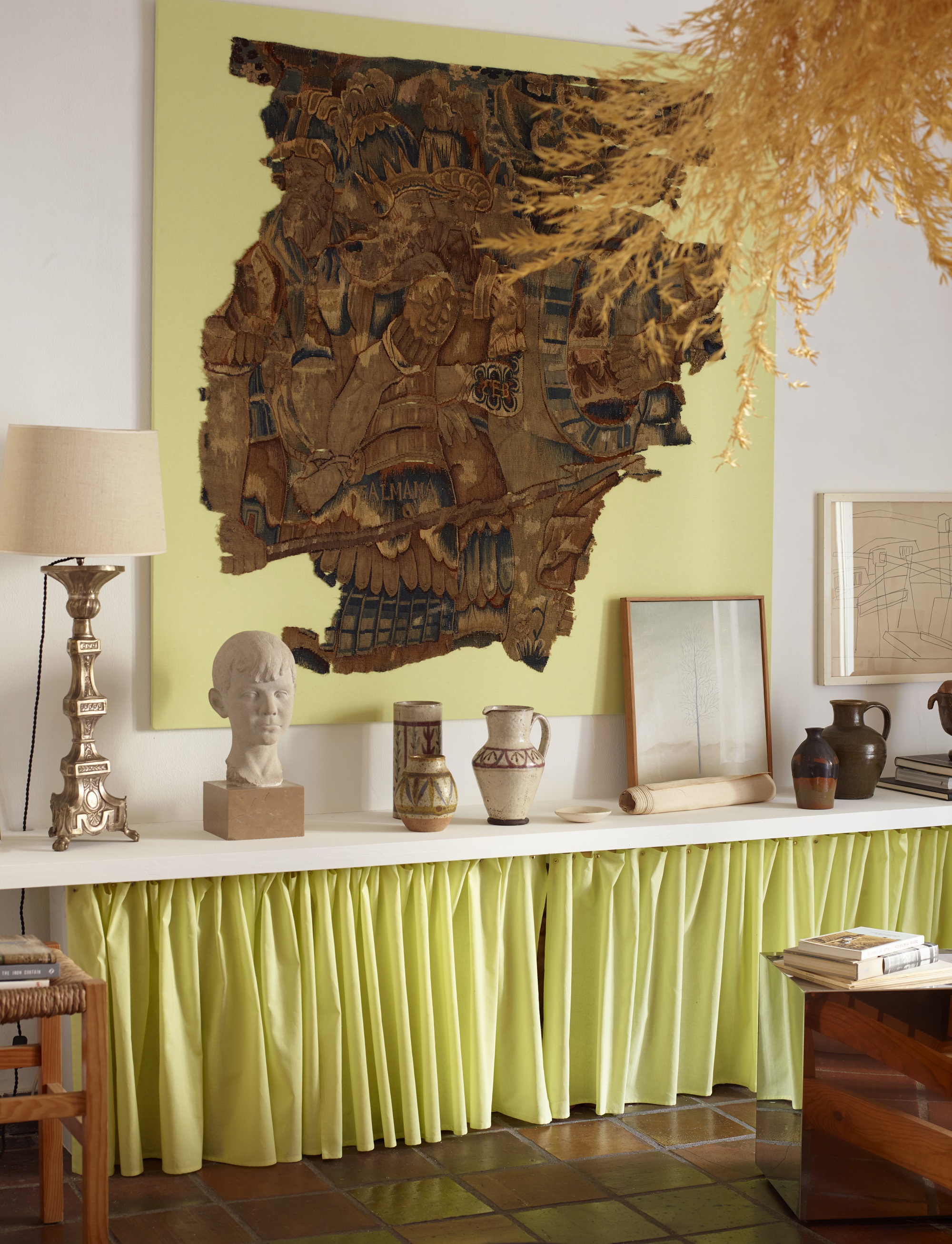 a room with a shelf filled with art with a neon yellow skirt underneath