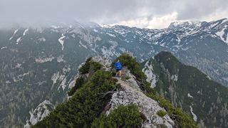 Ultra runner Galen Reynolds runs along a rocky mountain top, a stunning mountain view behind him.