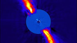 Beta Pictoris seen in infrared light (presented here in false color). A coronagraph has blotted out the glare of the star. The edge of the protoplanetary disk can be seen, along with light from one of its planets (the white dot near the center).
