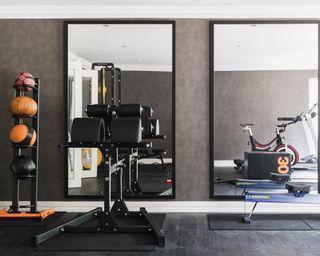 A home gym with two black framed large mirrors and machinery