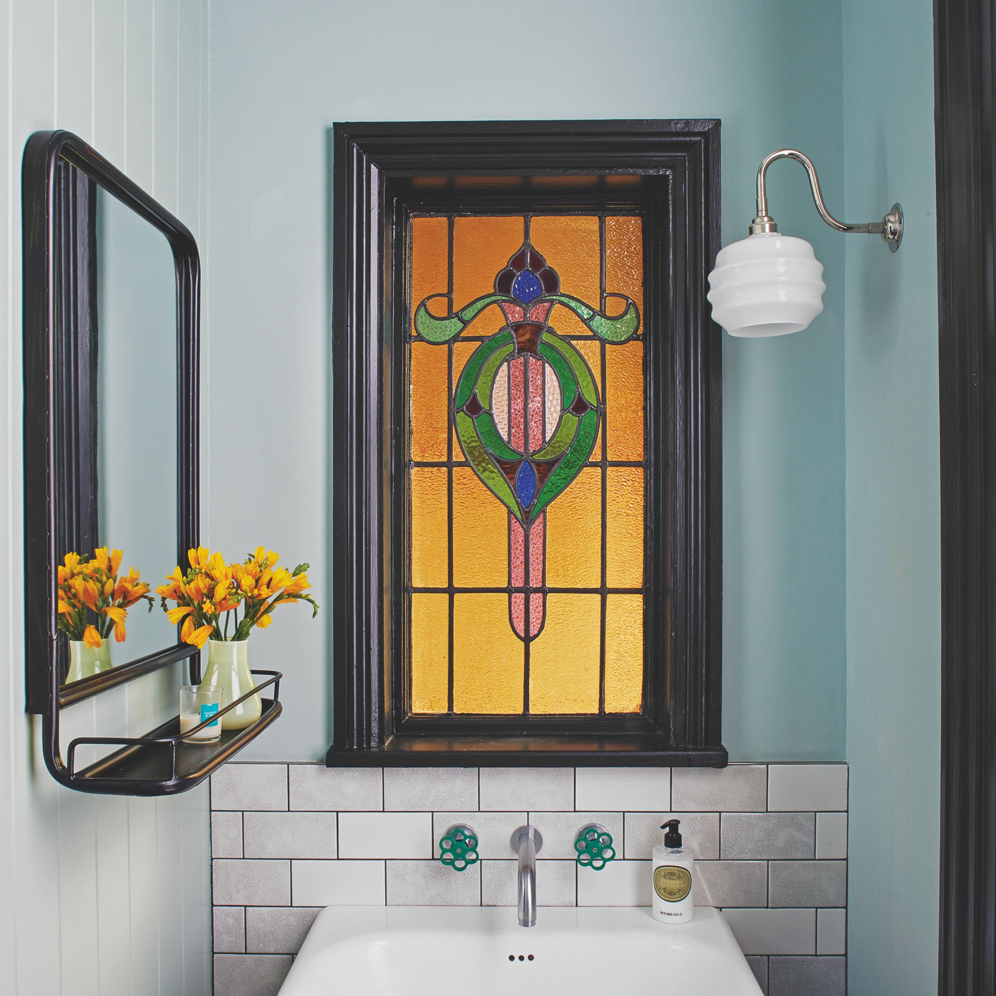 A bathroom with a yellow, pink, green and blue stained glass window