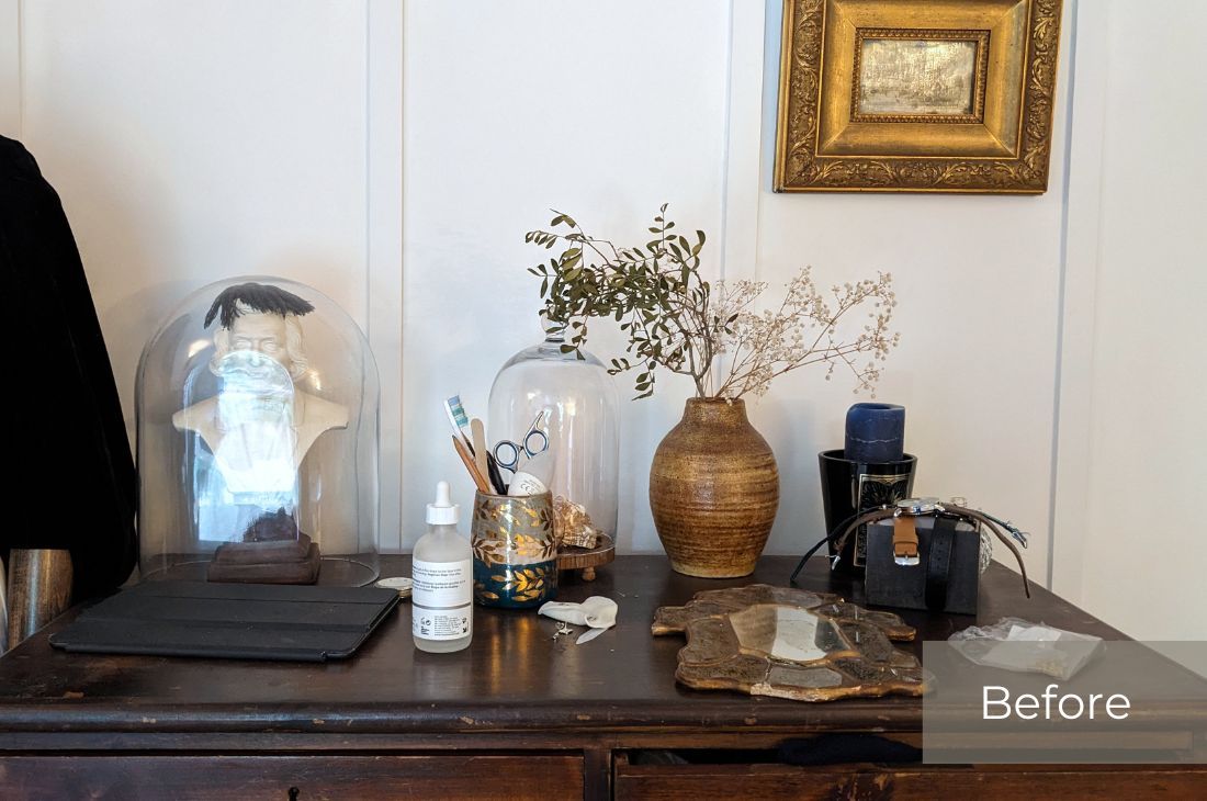 Before photos of of a dark ornate wooden dresses with vase, bottled products, terrariums and mirror laid flat on surface as well as a laptop in a black case