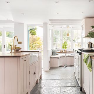White kitchen with pink island and grey slate floor