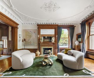 parlor with ornate ceiling and wood paneling and modern coffee table cream sofas and green rug