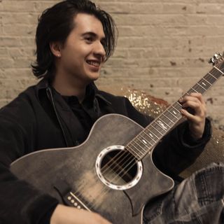 Marcin poses with his signature Ibanez acoustic guitar