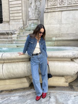 Anna LaPlaca wearing a collarless Madewell denim jacket, jeans, and red loafers