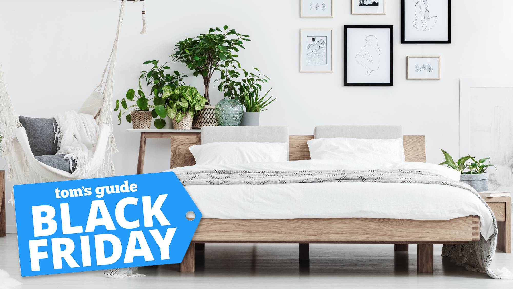 text says: Tom's Guide Black Friday, on top of a bedroom scene with a mattress on a wooden frame surrounded by pictures on the wall and plants