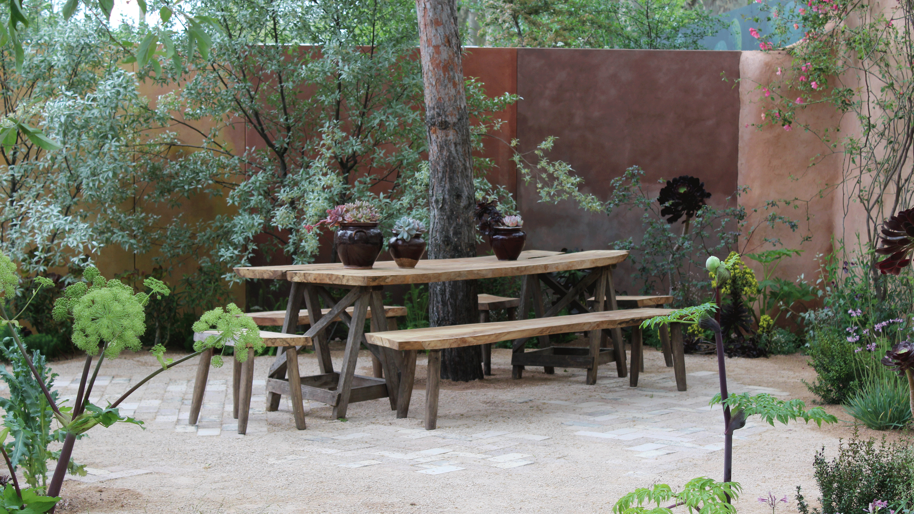 wooden decking with terracotta painted garden wall and large planters