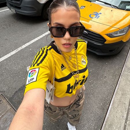 nadia idder wears a yellow football short, cmao shorts and white trainers