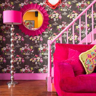 hallway with stair case and pink sofa and floral wallpaper wall