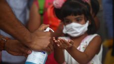 A child in Bangladesh receives a squirt of hand sanitizer to ward off COVID-19 in a March 2020 photo. There's been a sharp uptick in chemical burns from sanitizer to children's eyes since the start of the pandemic, largely due to public dispensers.