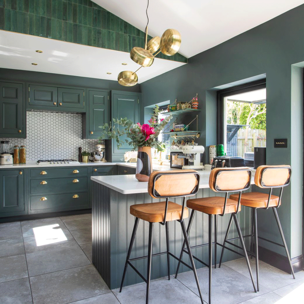 Kitchen with dark green cabinets, breakfast island with bar stools
