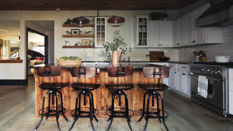 kitchen with wooden island, wood and metal bar stools, industrial style light and white cabinets and backsplash tiles