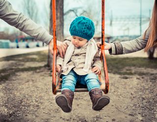 co-parenting parents pushing child on swing
