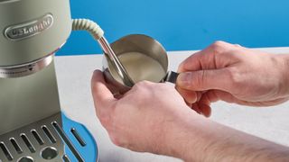 DeLonghi Dedica Duo in the green colorway with accessories photographed on a blue background.