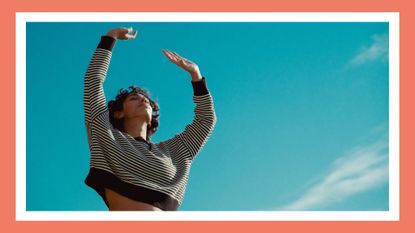 woman in a striped shirt with her hands to the sky