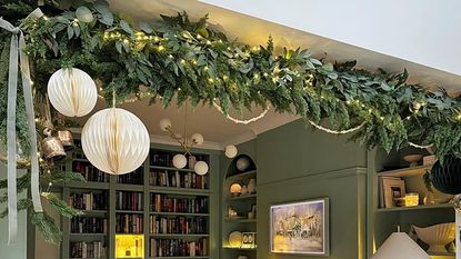 Living room with Christmas garland, paper decorations and green walls.