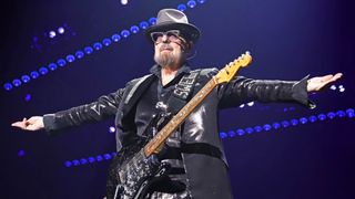 Dave Stewart spreads his arms out wide as he performs live with a custom black Stratocaster.