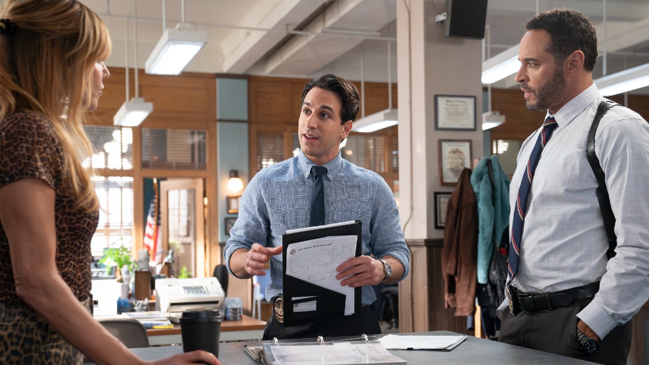From left to right: Kaitlin Olson is looking at Deniz Akdeniz who is looking at her while talking. Daniel Sunjata is standing to his right.