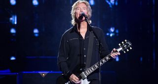 Brian Ray wears all-black and plays a black Gibson SG with white pickguard.