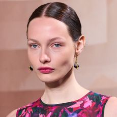 Model from Ulla Johnson spring 2025 show wearing dangling earrings and pink lipstick 