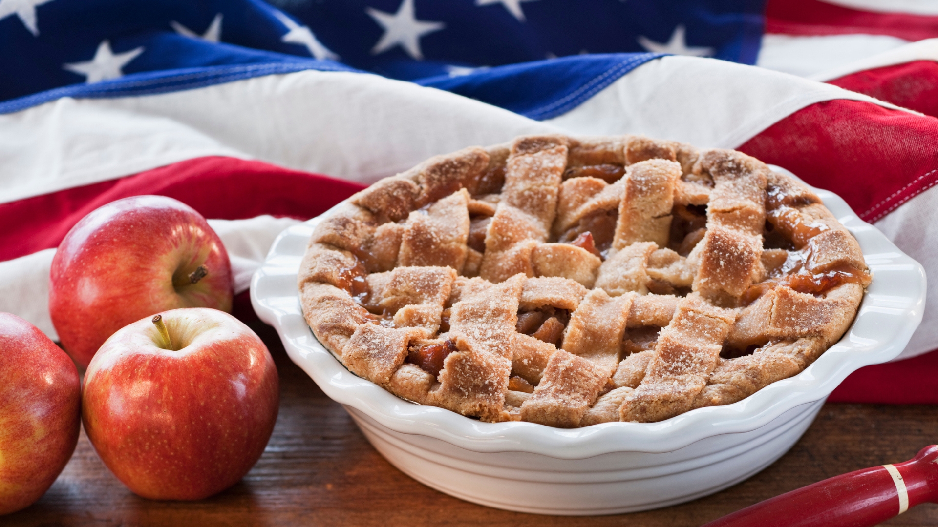 A fresh apple pie in a pie dish atop the USA flag