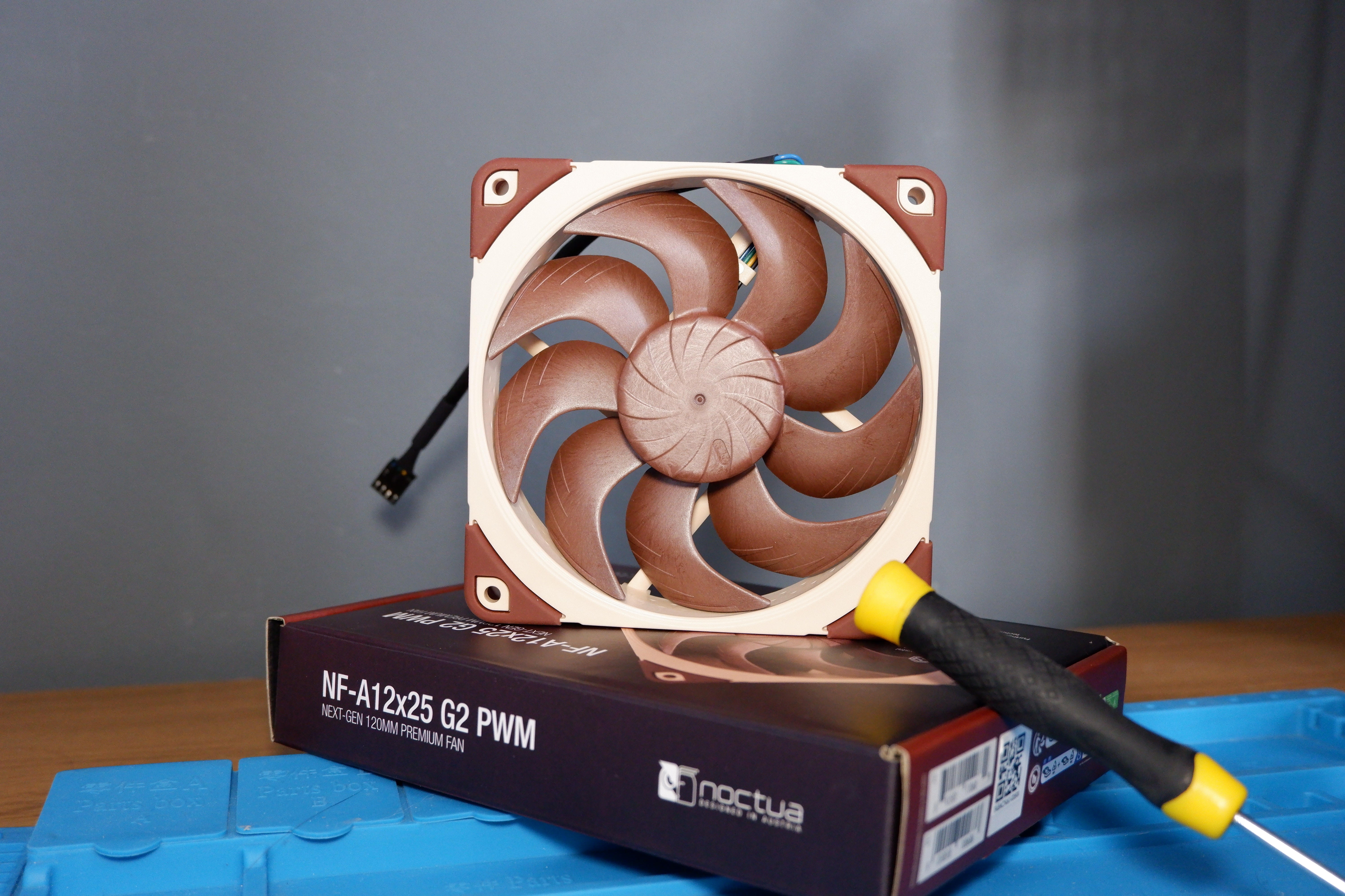 A set of Noctua NF-A12x25 G2 PC fans on a desk with packaging.