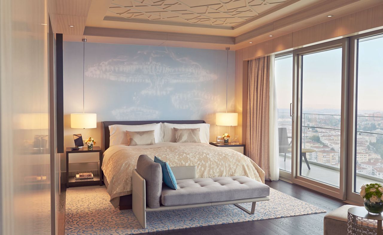 Bedroom of the Raffles Hotel, Istanbul with balcony, cream bedding and wooden floors with patterned carpet