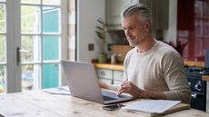 A gray-haired man sits at a computer