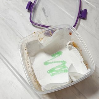 Cleaning food container with paper towel, washing up liquid, and water