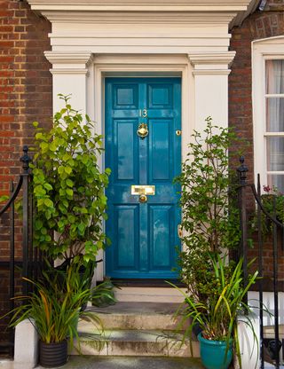 house exterior with blue door brick walls and potted plants