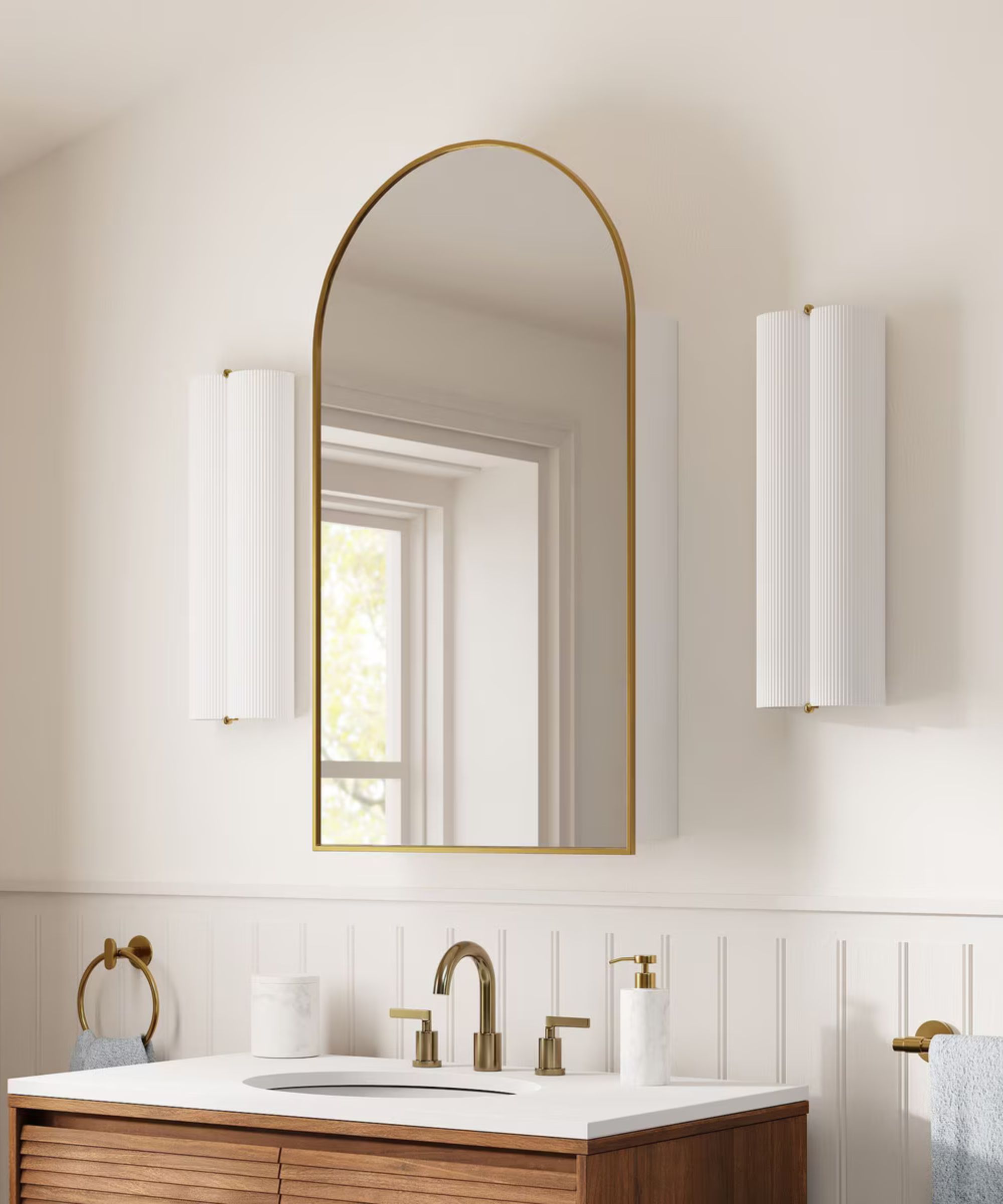 A white bathroom with a wood vanity and arched mirrored cabinet