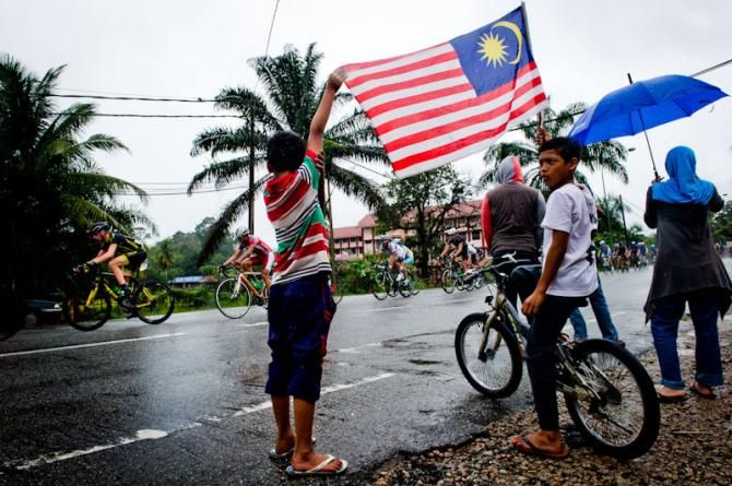 Local kids raising a Malaysian flag in Le Tour de Langkawi 2012