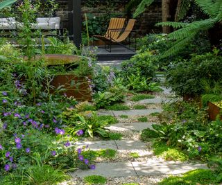 A small back garden with a seating area at the bottom and a permeable green pathway leading to it