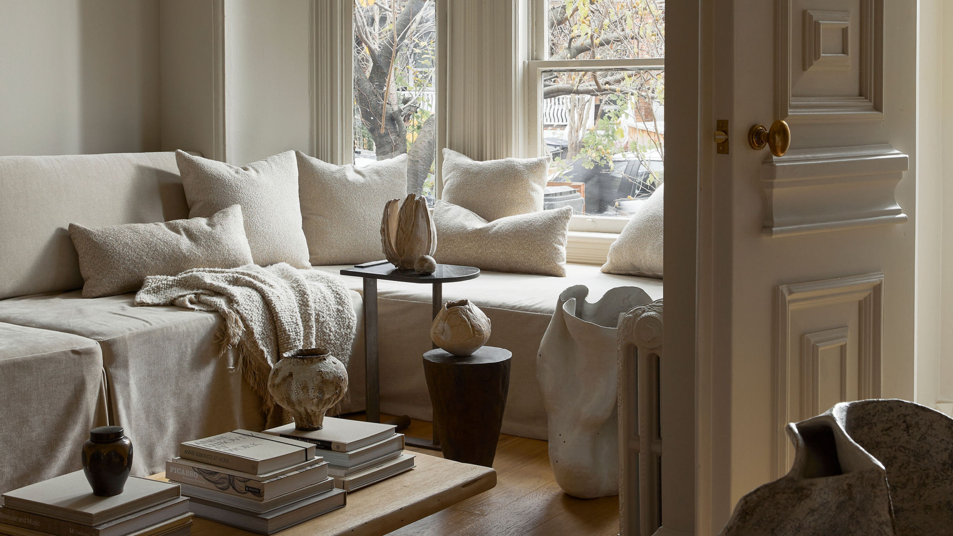 all white living room in a victorian property with lots of ceramic work around the sitting area 