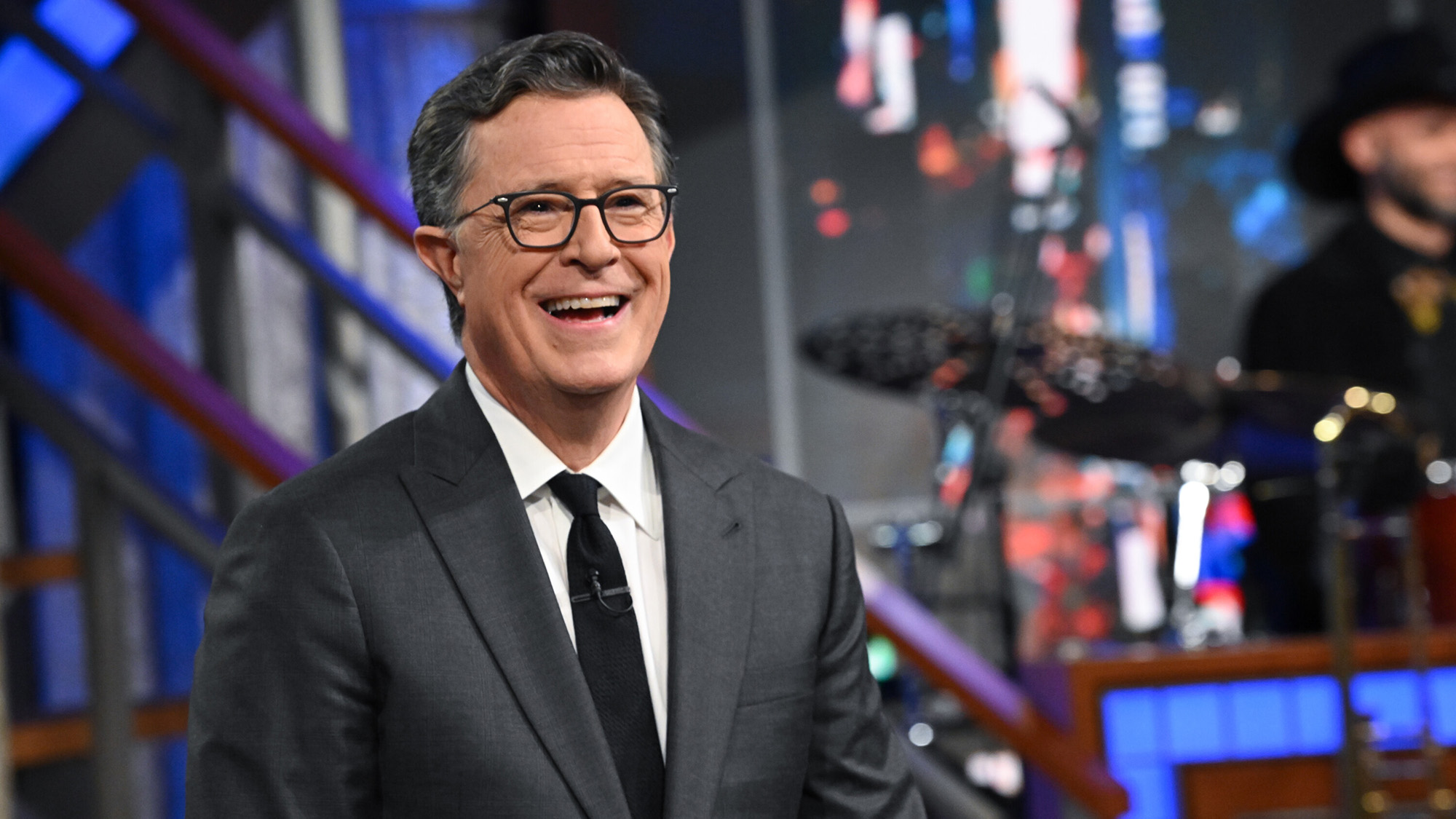 Stephen Colbert beams ahead of his show ending while standing next to his Late Show band at the Ed Sullivan theater. 