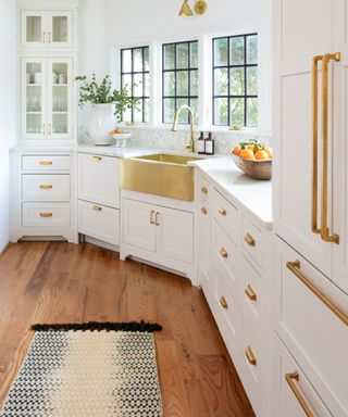 should I use handles or knobs on kitchen cabinets, white kitchen with brass handles and knobs, brass sink, hardwood floor, rug