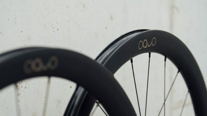 A close up shot of the top of a OQUO Road wheelset leaning against a concrete wall