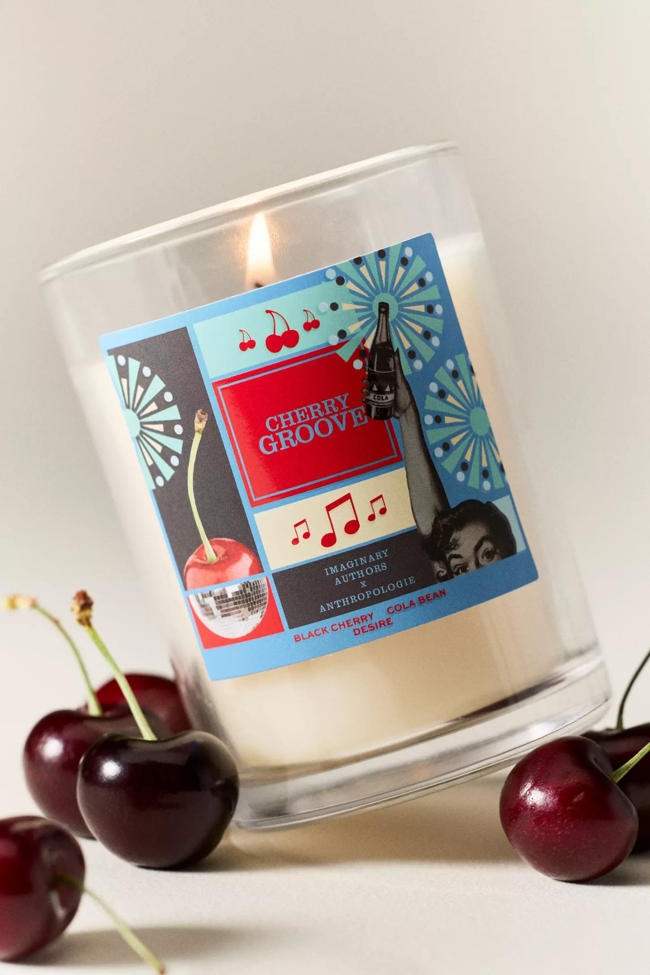 A glass candle by burgundy cherries