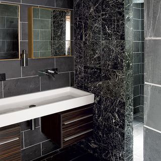 bathroom with black tiles wall and washbasin and shower