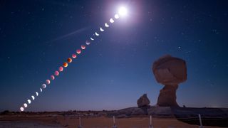 A composite image showing the phases of a blood moon total lunar eclipse unfolding in a line through a starry sky above a desert featuring two large chalk formations.