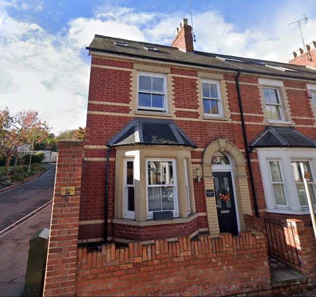 A red brick house with a brick wall in front