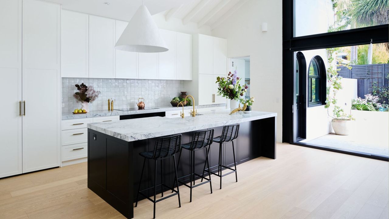 A clean home with white cabinets and a chic marble island in the middle 