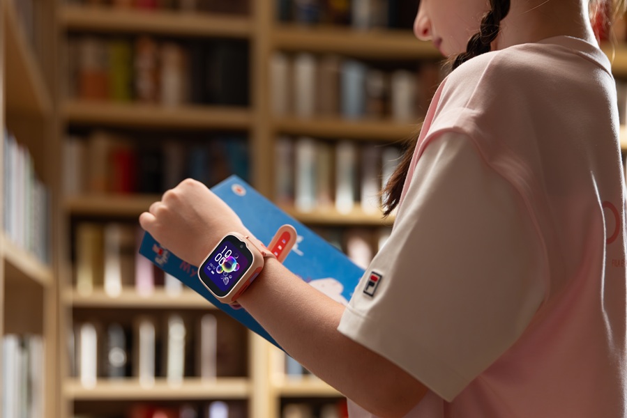A pink TCL MOVETIME MT48 smartwatch on a young model in a library.