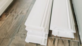 Close up of stacked pre-painted skirting boards on wooden laminate flooring